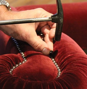 Tetrad craftsperson applying individual upholstery studs by hand